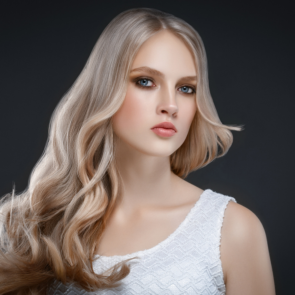 Красивая длинноволосая блондинка с голубыми глазами на сером фоне