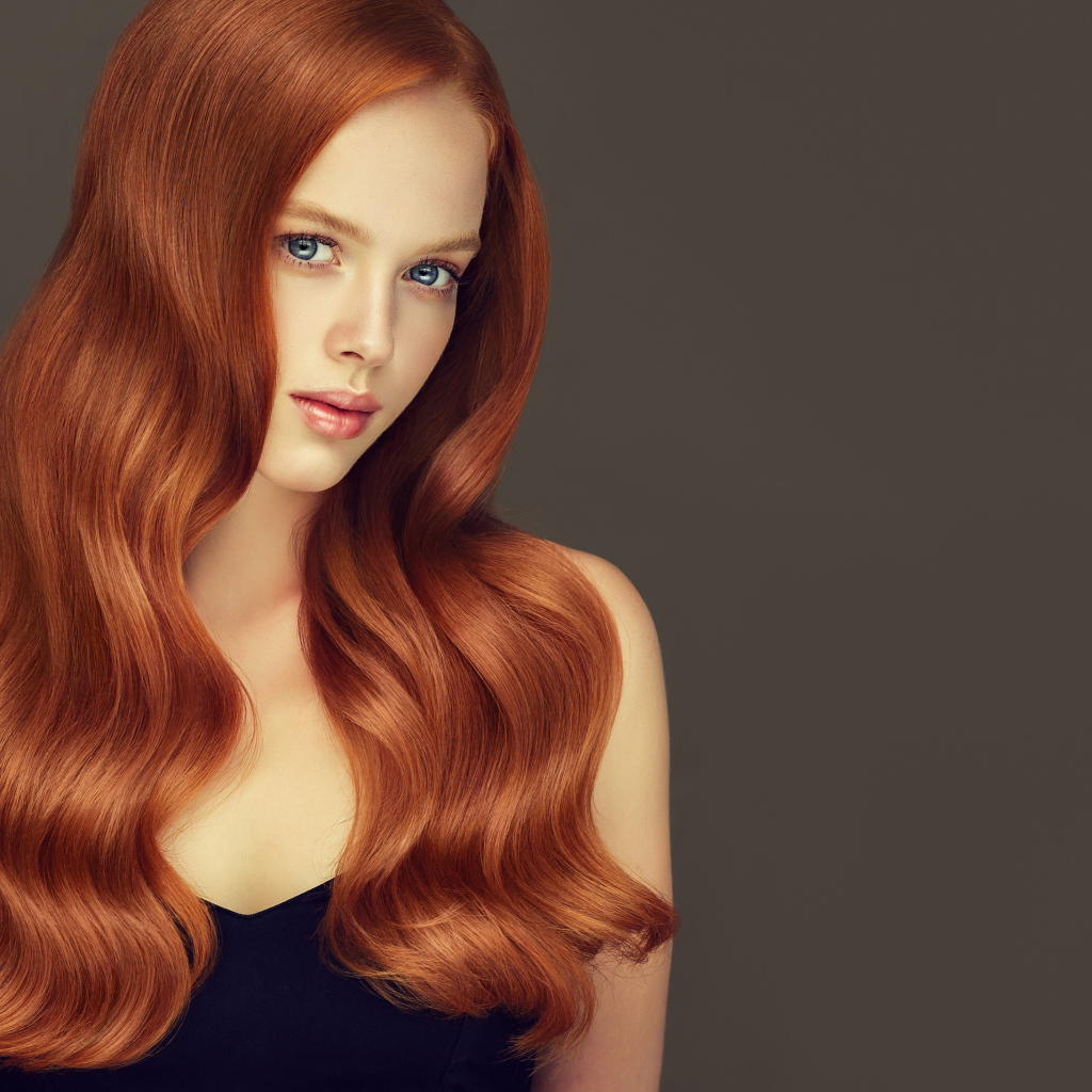 Красивая рыжеволосая голубоглазая девушка на сером фоне