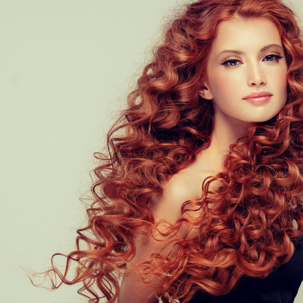 Красивая рыжеволосая девушка на сером фоне