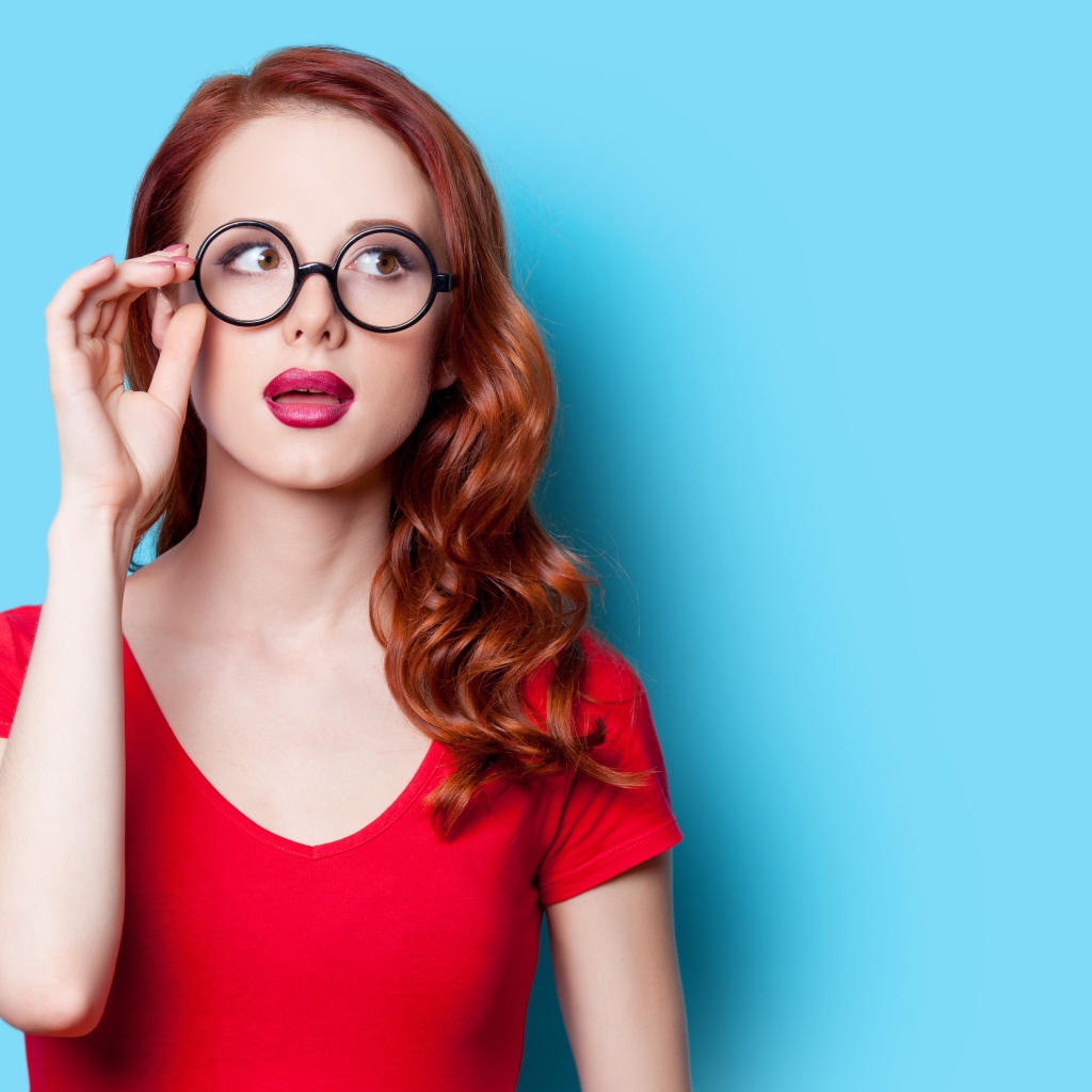 Красивая рыжеволосая девушка в очках на голубом фоне