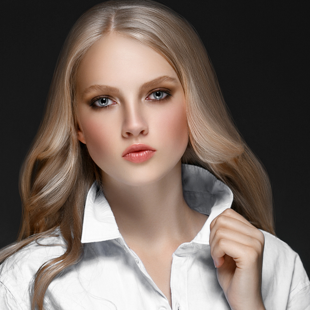 Красивая стильная голубоглазая блондинка в белой рубашке на сером фоне