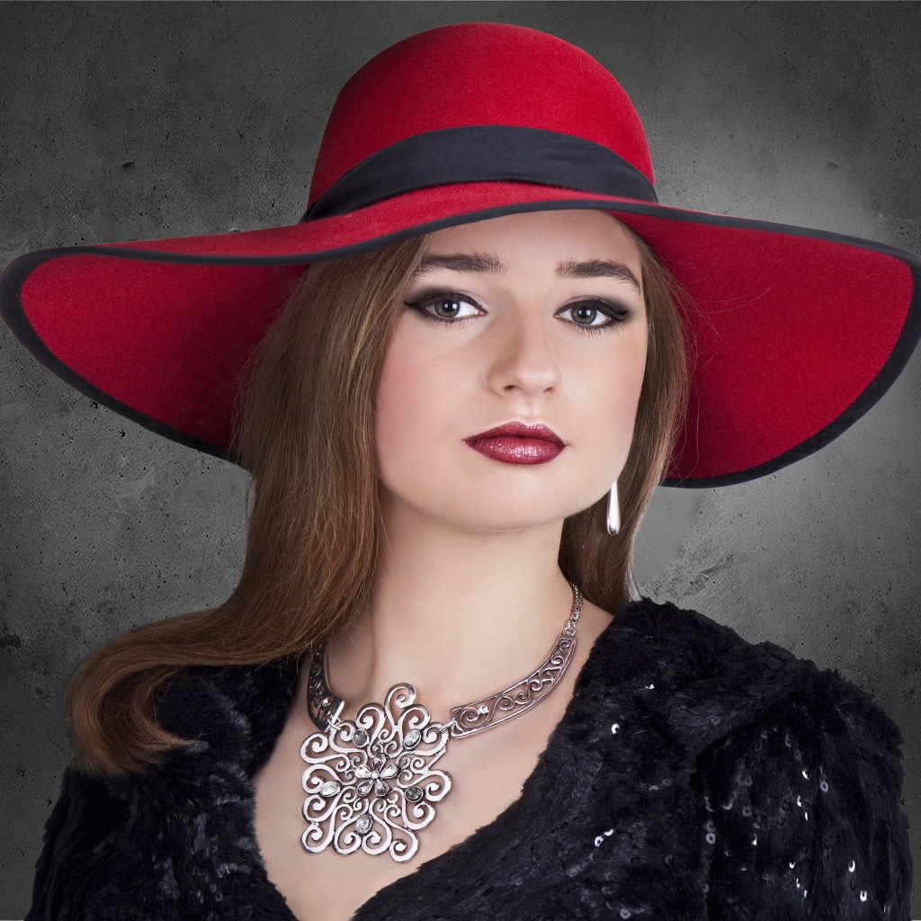 Красивая стильная девушка в красной шляпе с украшением на шее 