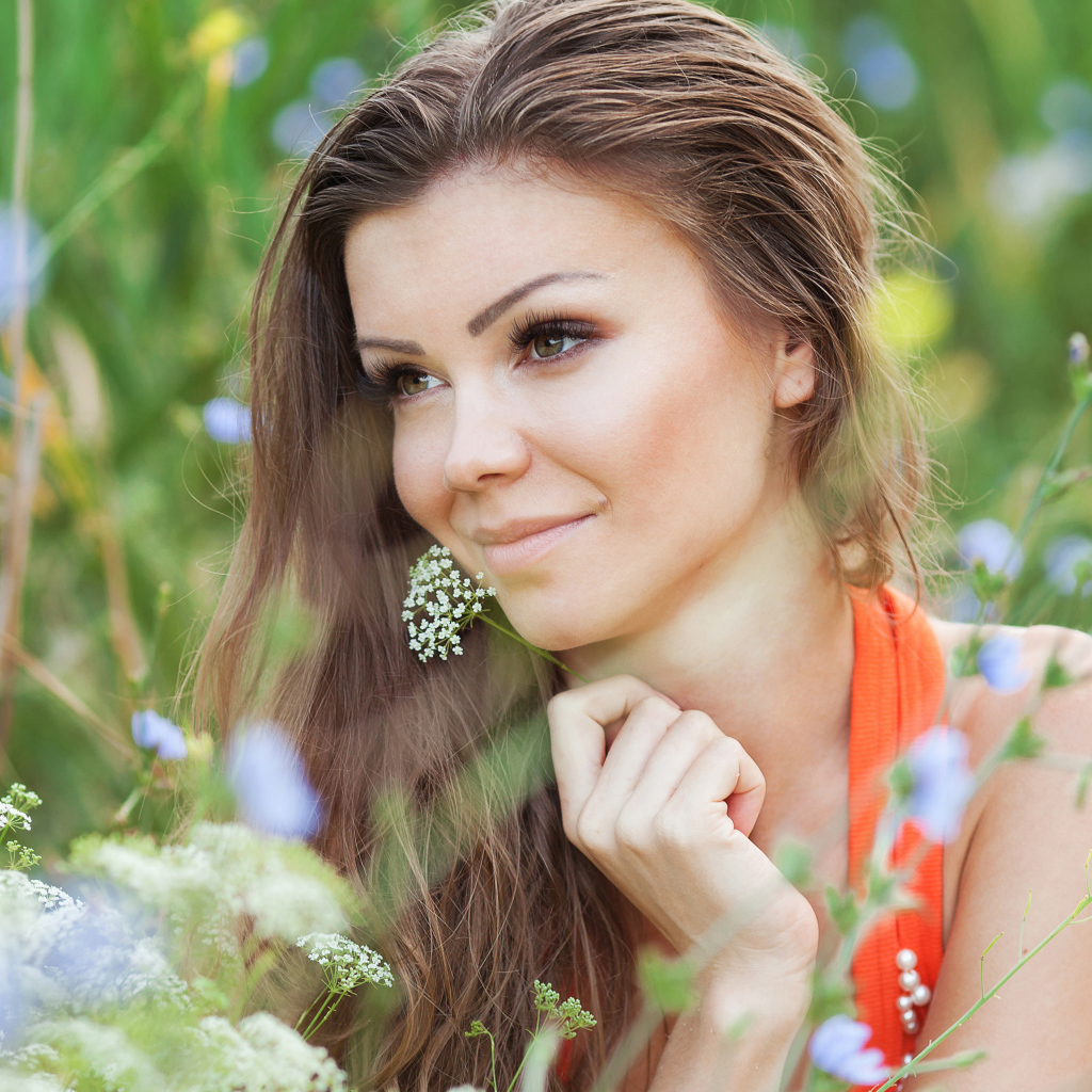 Красивая нежная девушка лежит в цветах на поле