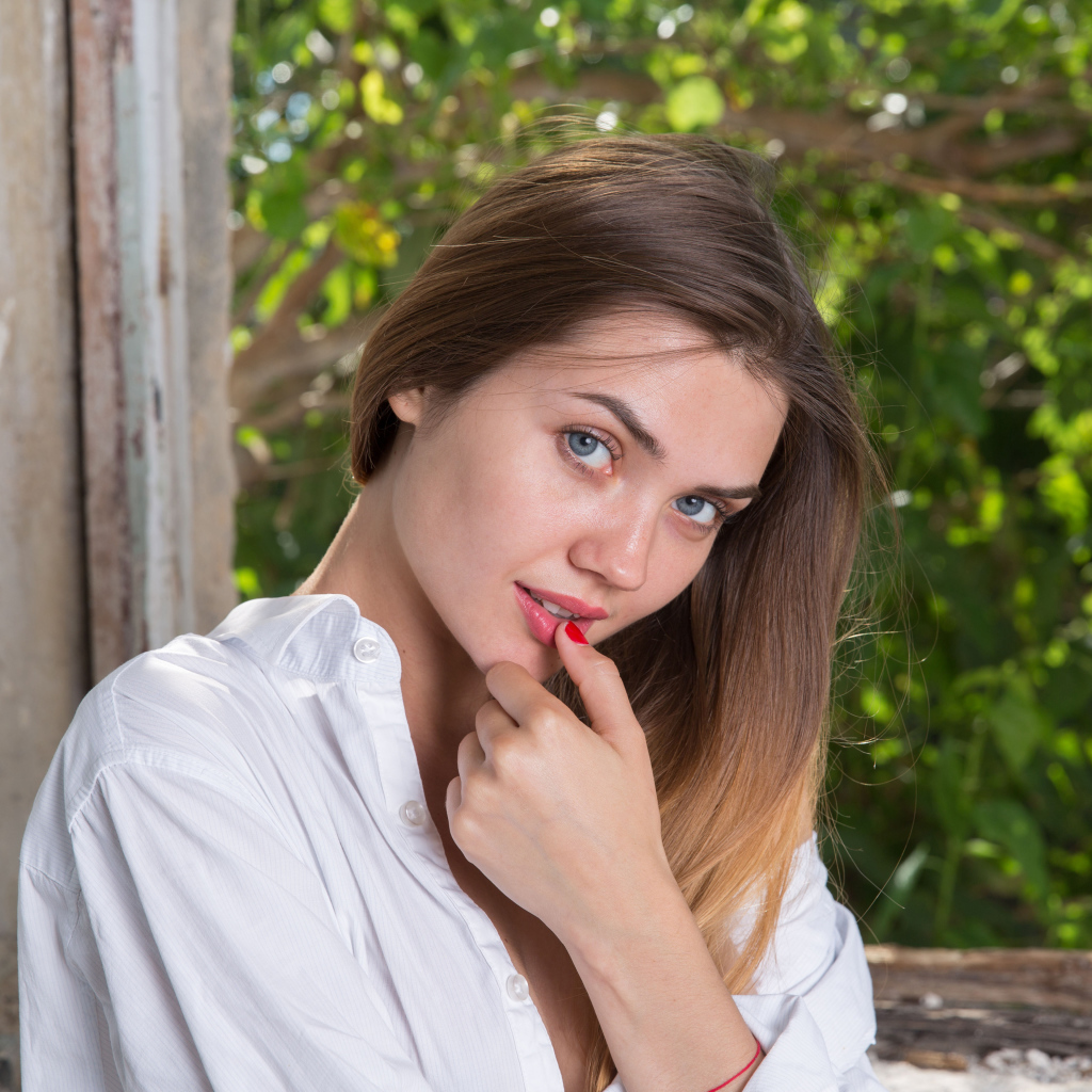 Красивая нежная девушка с серыми глазами с пальцем у рта