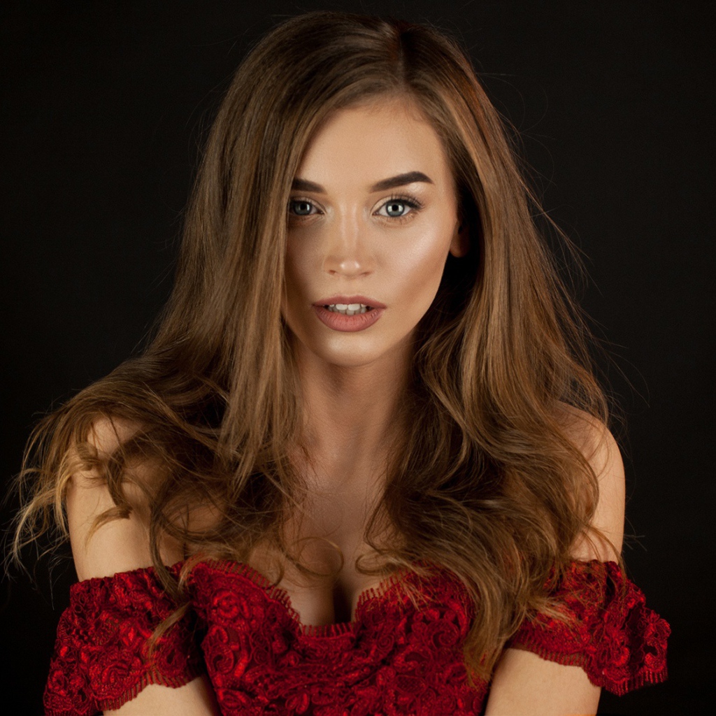 Красивая нежная длинноволосая шатенка в красном платье на черном фоне