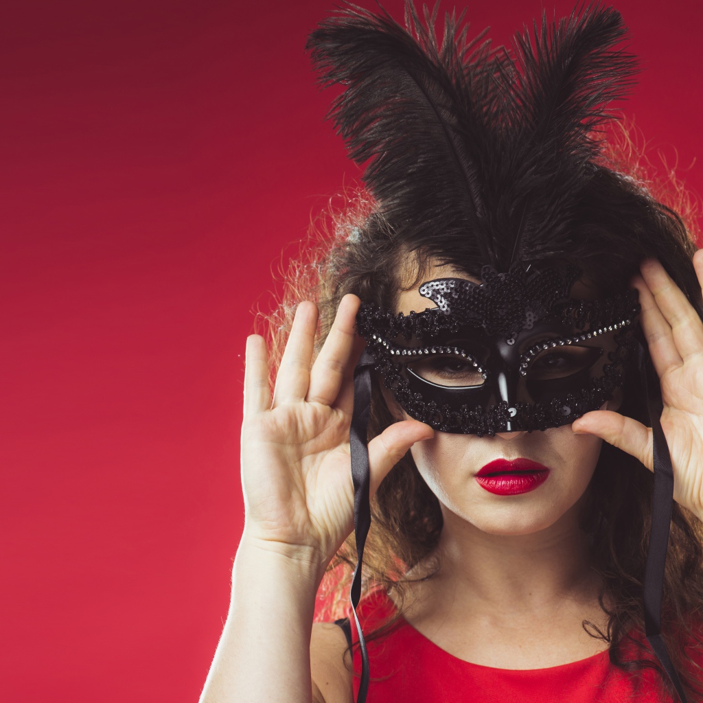 Красивая женщина в черной маске на красном фоне
