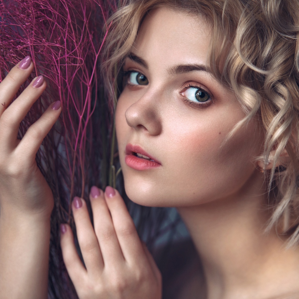 Красивая молодая блондинка с красным растением в руках