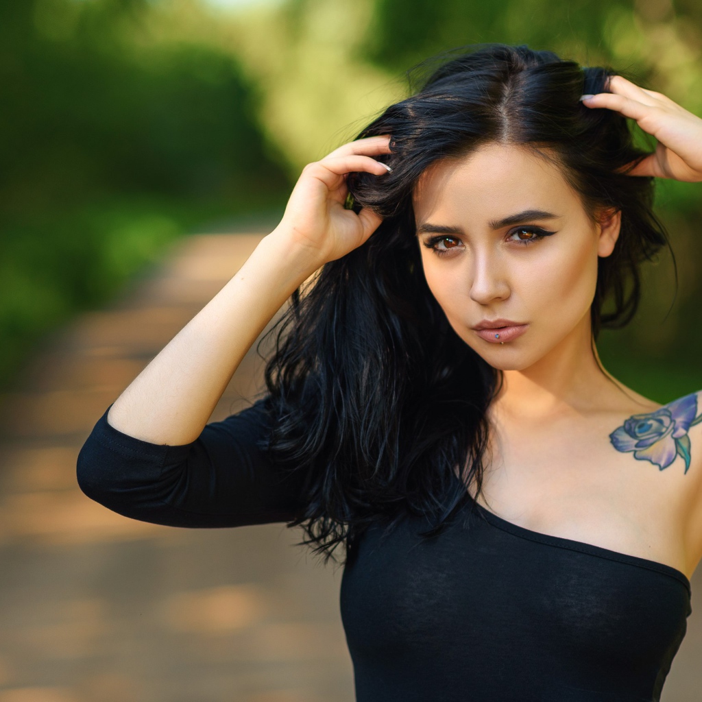 Красивая молодая девушка в черном с татуировкой на руке