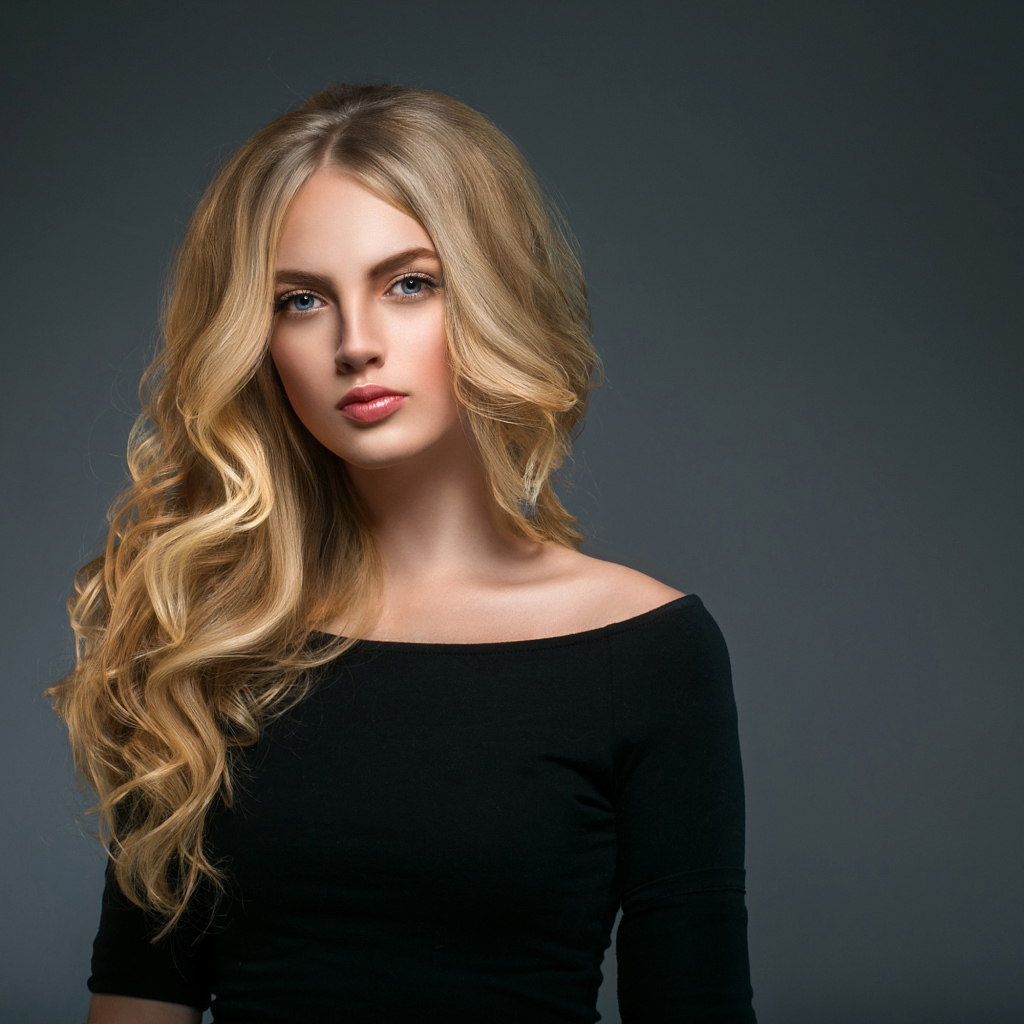 Красивая молодая девушка с длинными волосами в черном наряде на сером фоне