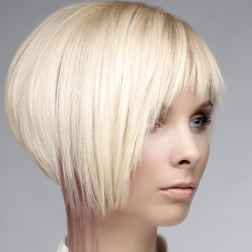 Голубоглазая девушка блондинка с короткой стрижкой на сером фоне