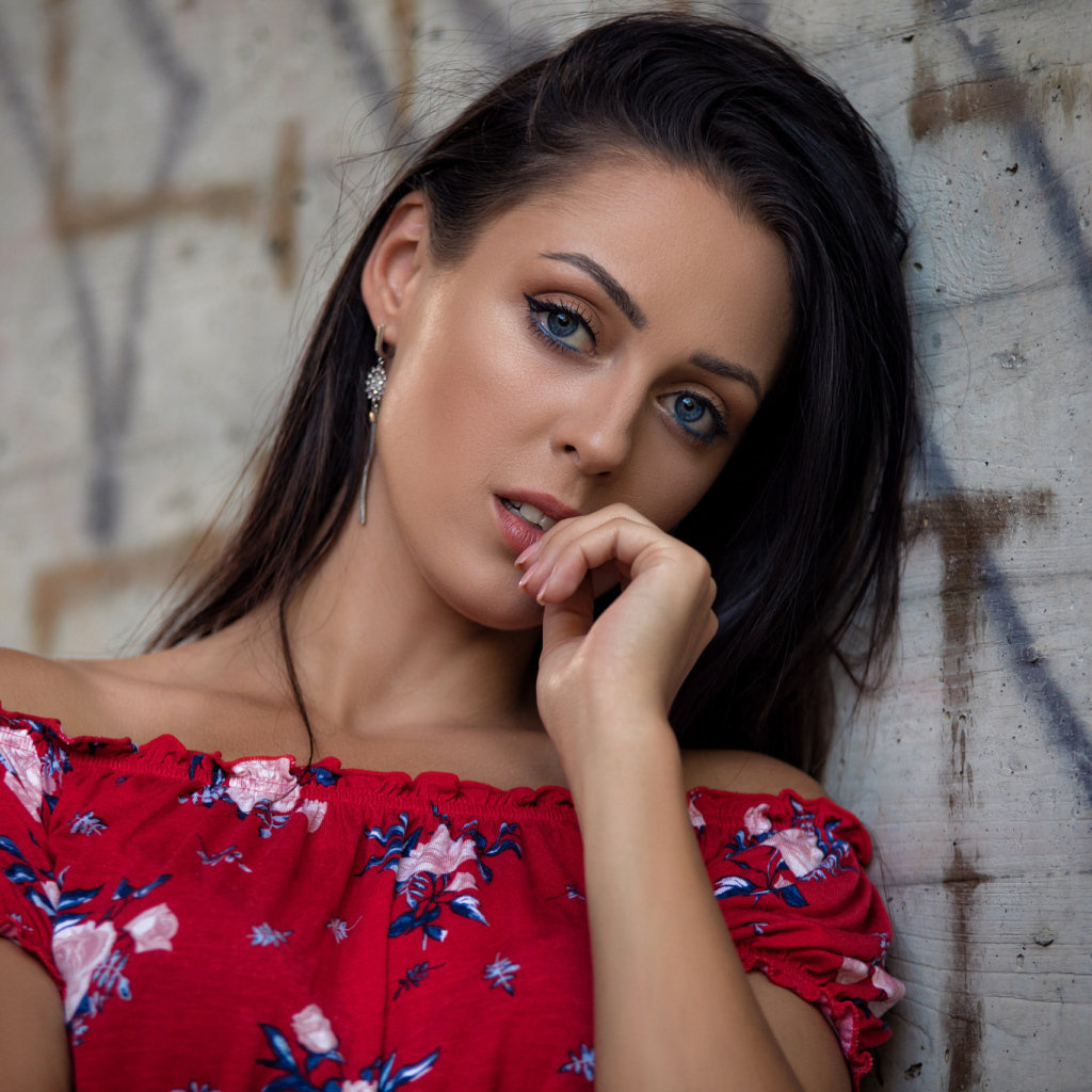 Голубоглазая брюнетка стоит в платье стоит стены