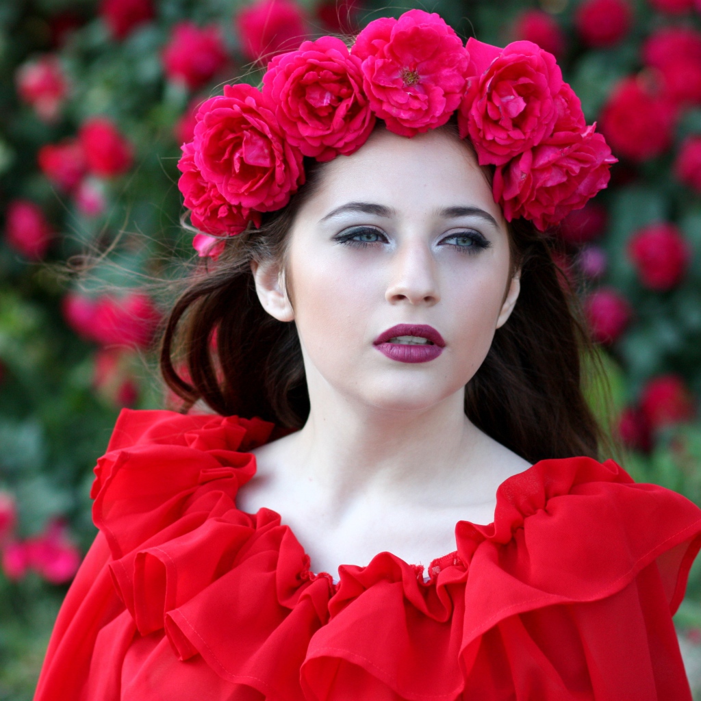 Яркая девушка в красном платье с венком из роз на голове