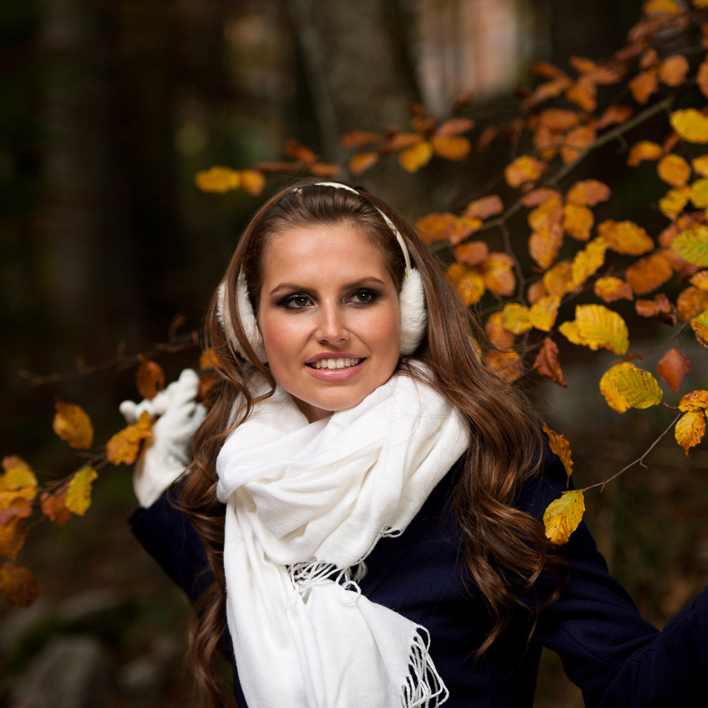 Девушка шатенка с белым шарфом стоит у дерева с желтыми листьями