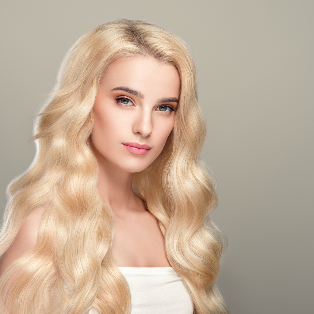 Милая длинноволосая блондинка на сером фоне