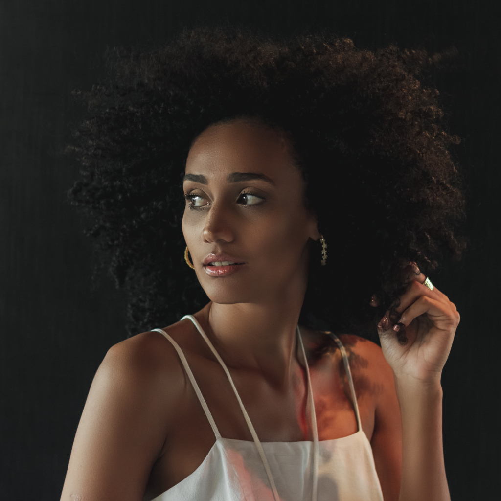 Темнокожая девушка с красивыми волосами на сером фоне