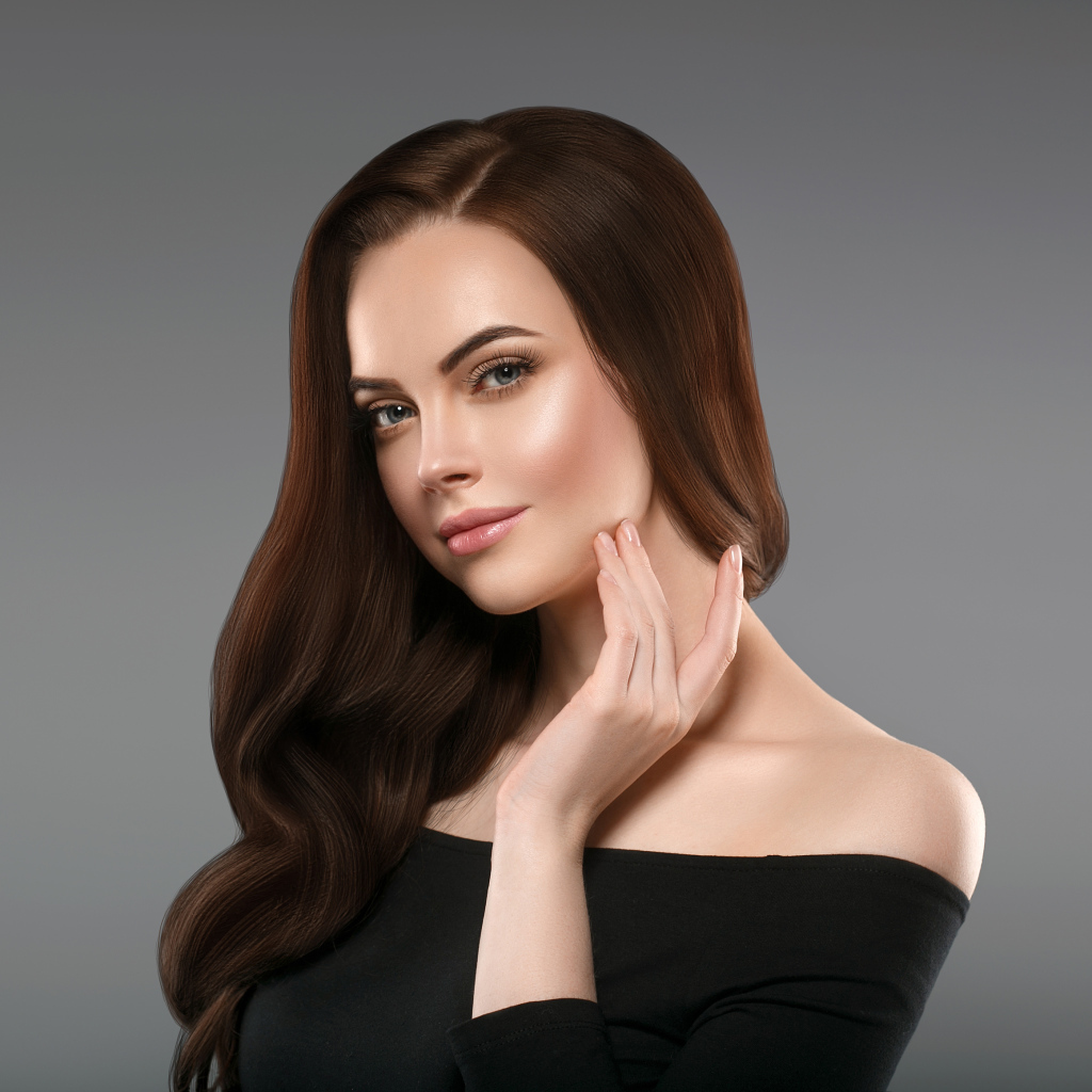 Нежная длинноволосая шатенка в черном платье на сером фоне