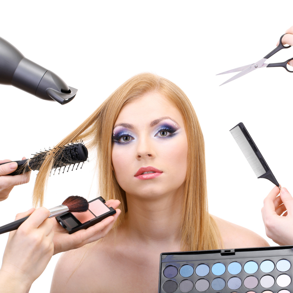 Девушке делают макияж и прическу на белом фоне