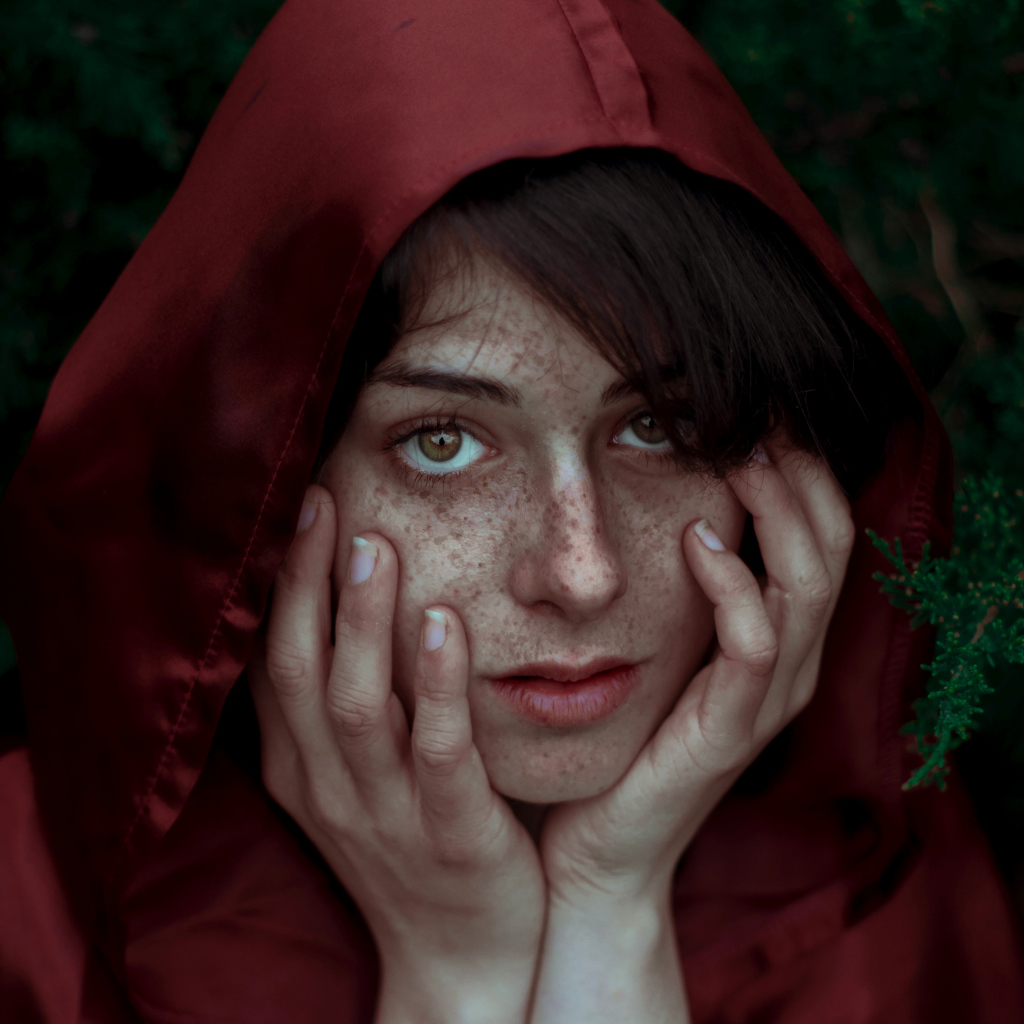 Девушка в красном плаще с веснушками на лице