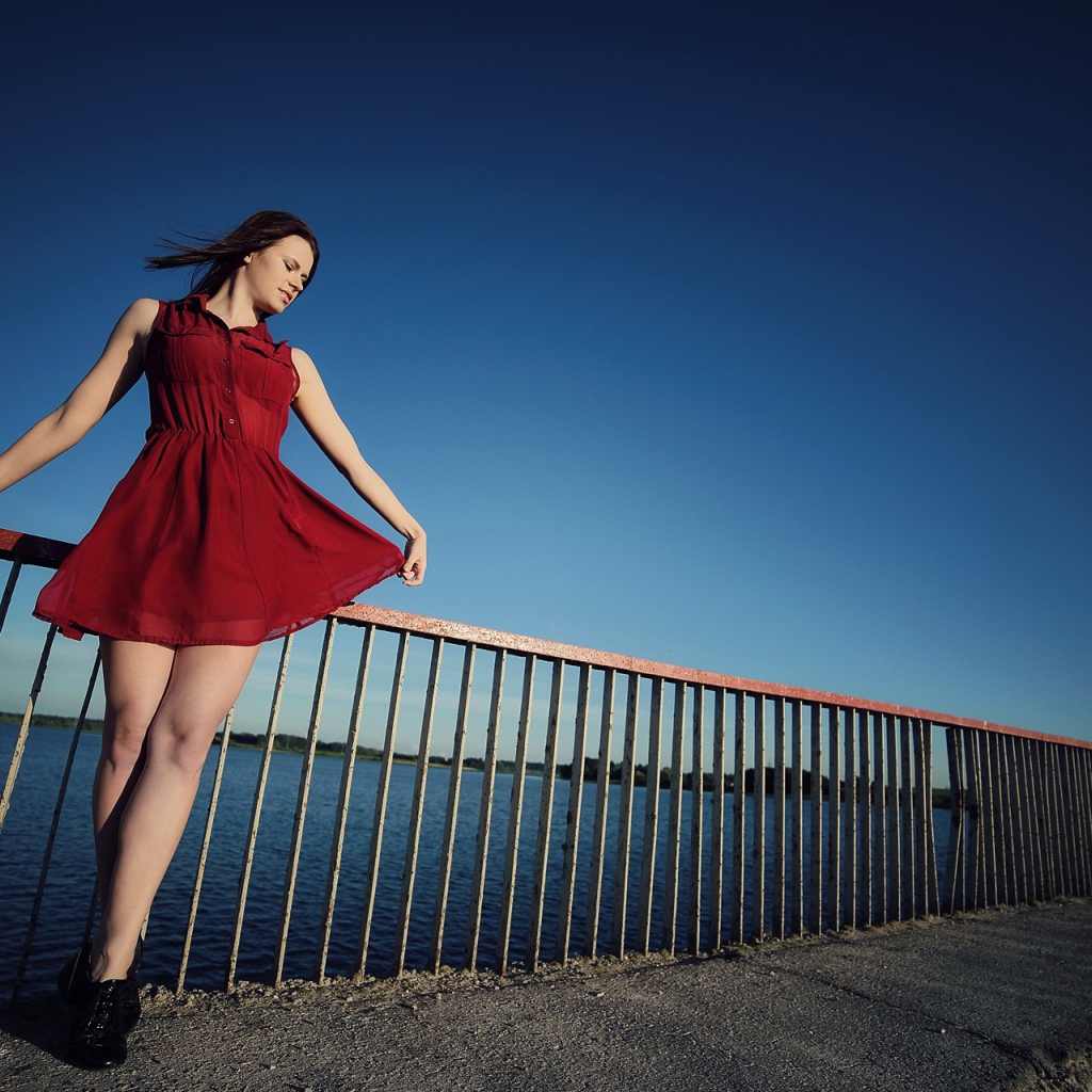 Девушка в коротком красном платье на мосту 