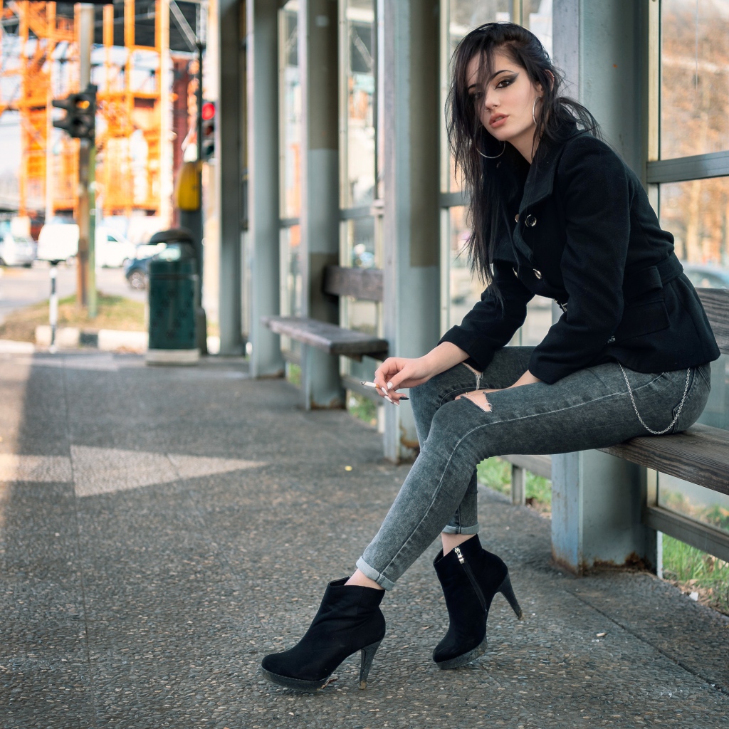 Девушка неформалка сидит на автобусной остановке