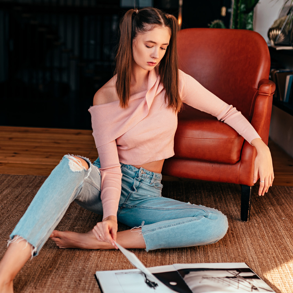 Девушка читает журнал на полу у кожаного кресла