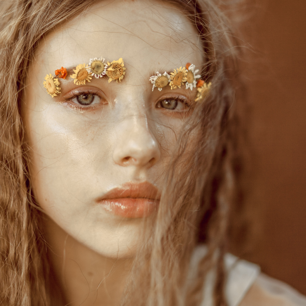 Девушка с цветами на бровях крупным планом
