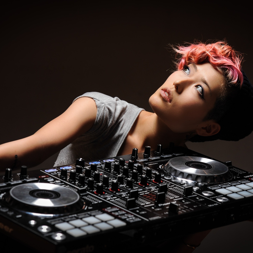 Девушка с розовой челкой с диджейским пультом в руках