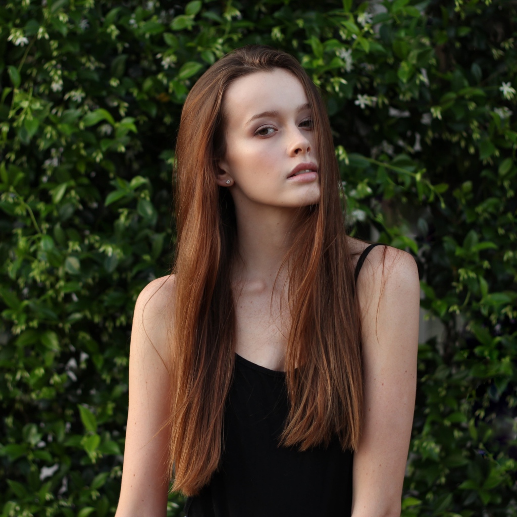Длинноволосая шатенка на фоне зеленых зарослей