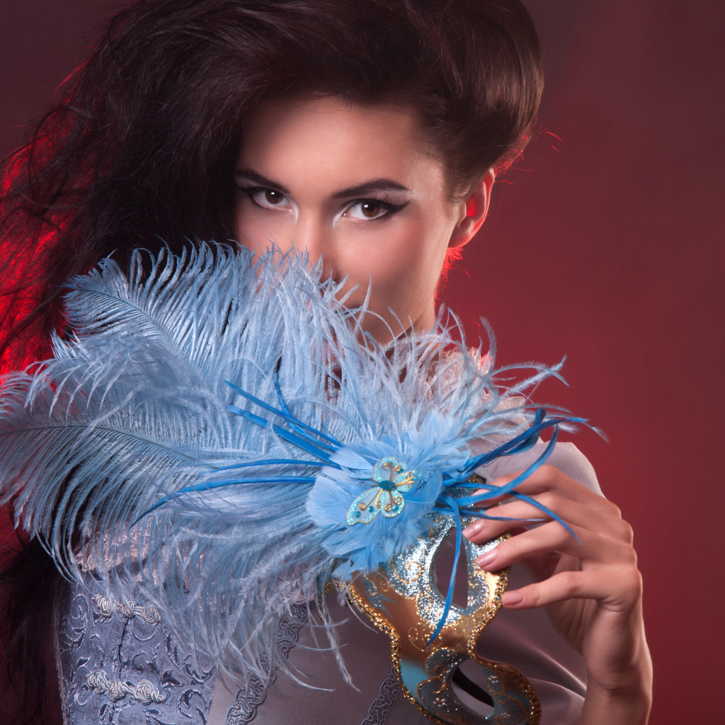 Длинноволосая девушка с маской с перьями в руке