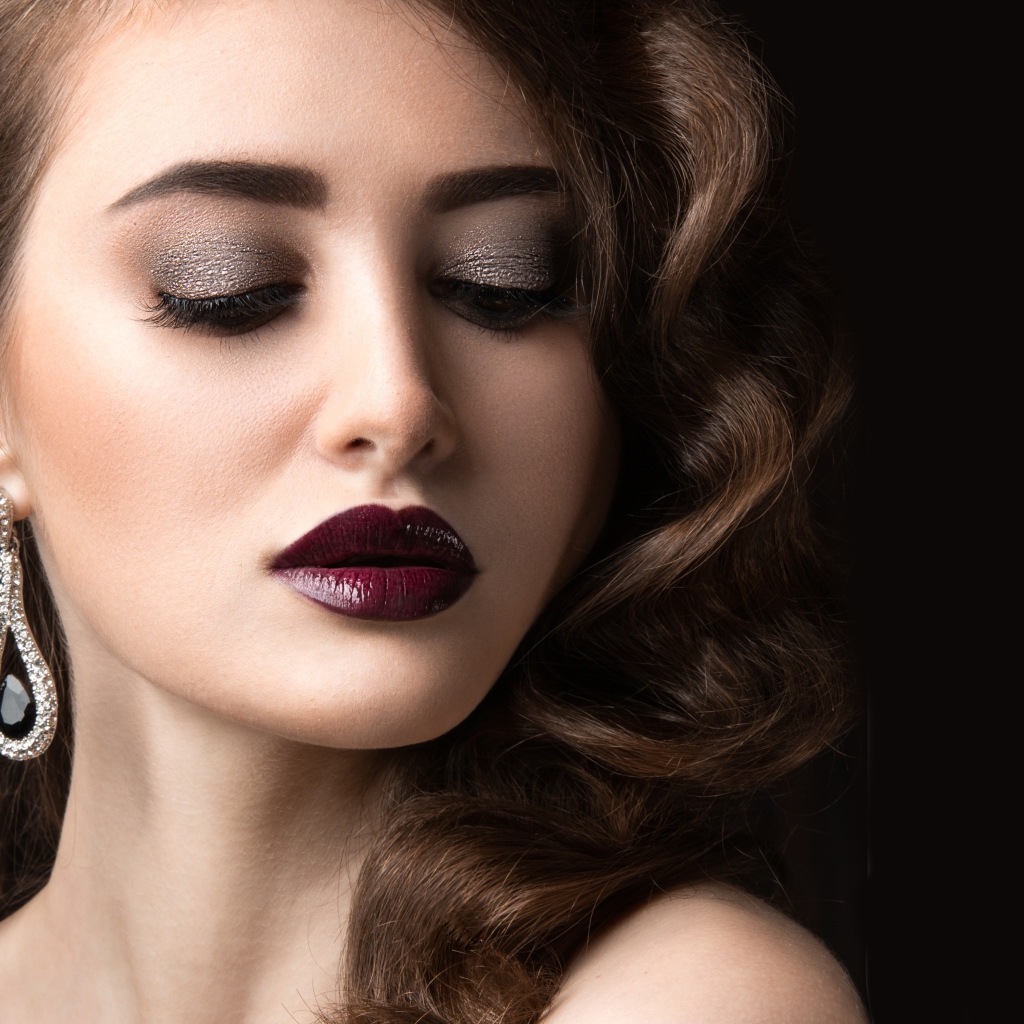 Длинноволосая девушка с ярким макияжем на черном фоне