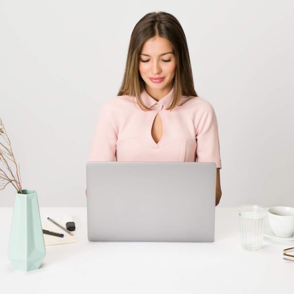 Умная девушка за ноутбуком на сером фоне