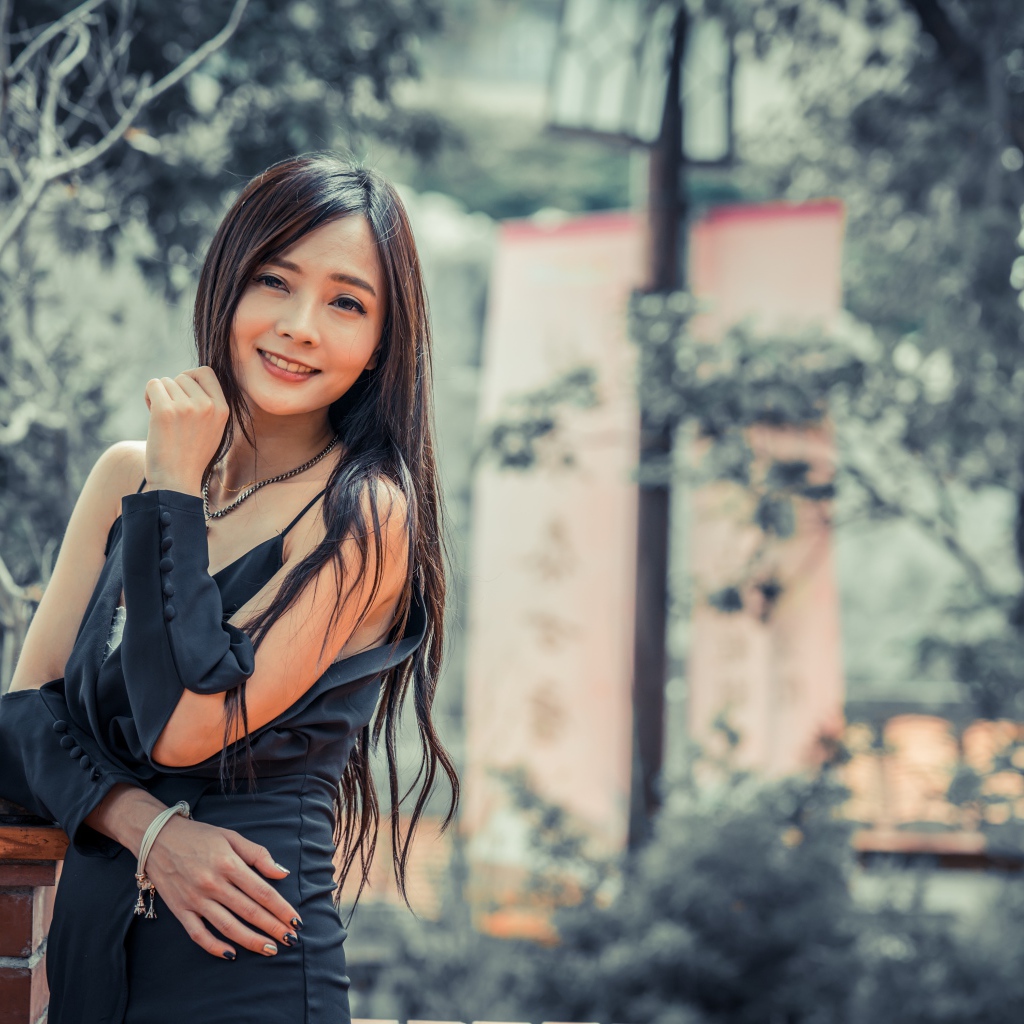 Улыбающаяся девушка азиатка в черном платье