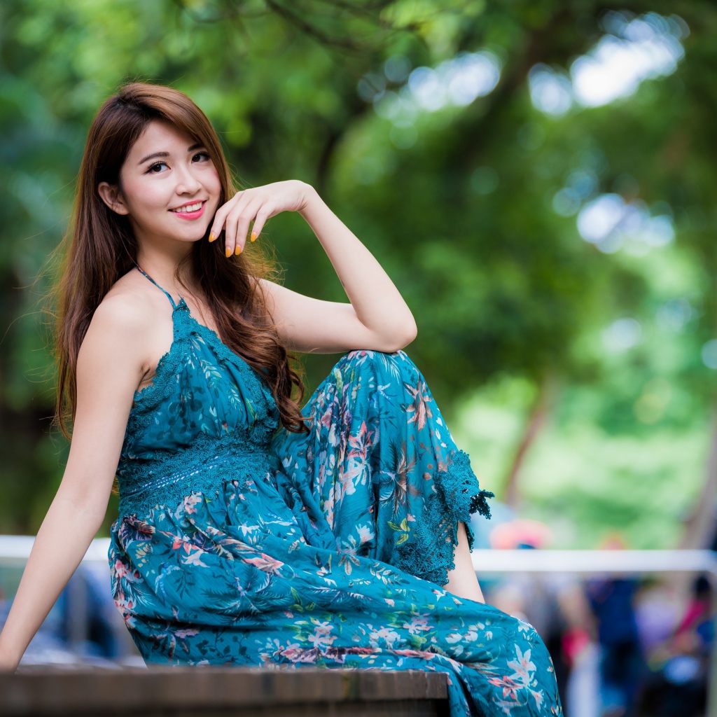 Улыбающаяся азиатка сидит на лавке