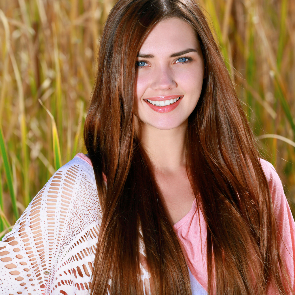 Улыбающаяся голубоглазая шатенка на поле