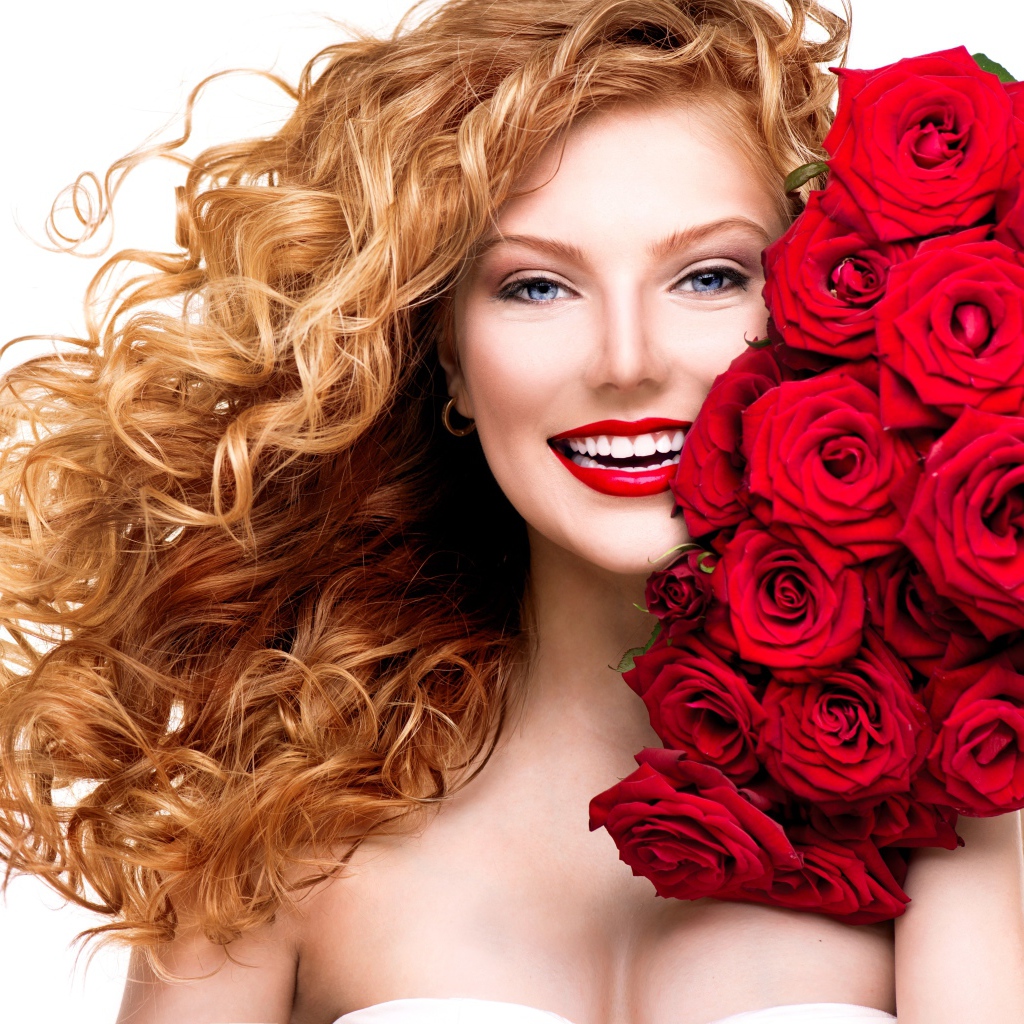 Улыбающаяся голубоглазая рыжеволосая девушка с букетом красных роз 