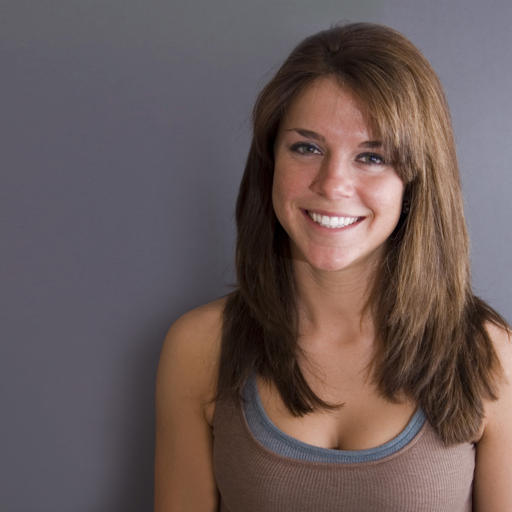 Улыбающаяся милая девушка у серой стены