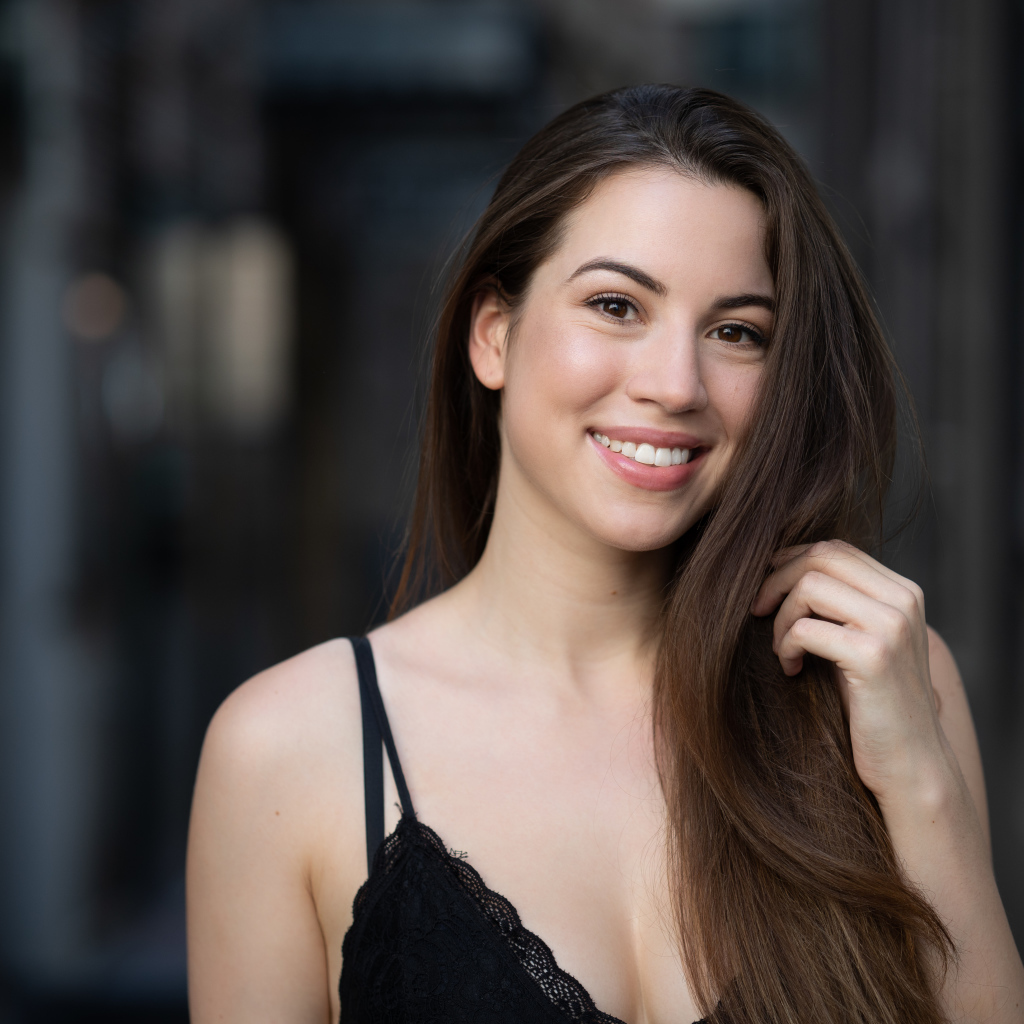 Улыбающаяся девушка держит длинные волосы