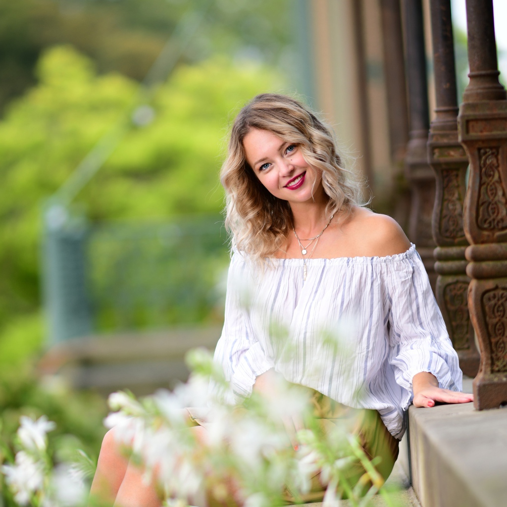 Улыбающаяся девушка сидит на ступенях