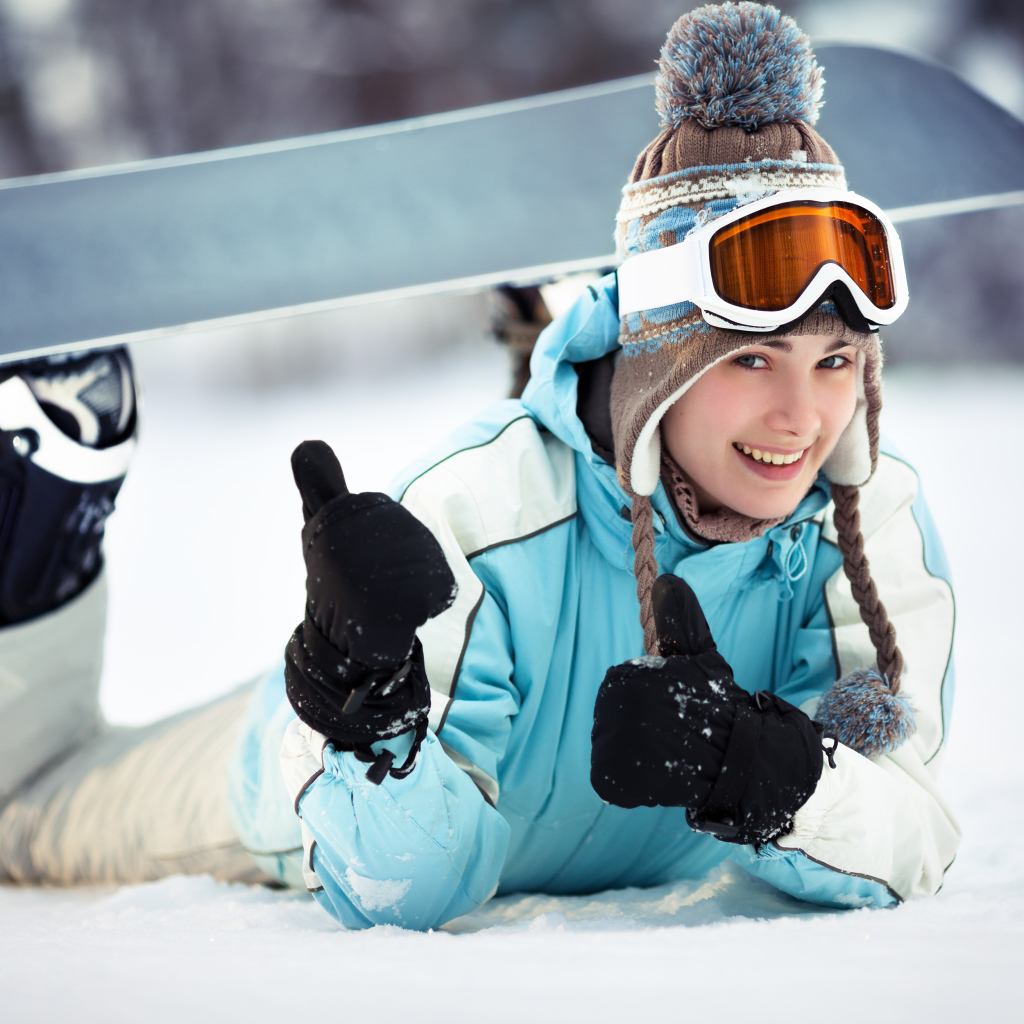 Улыбающаяся девушка сноубордистка на снегу зимой