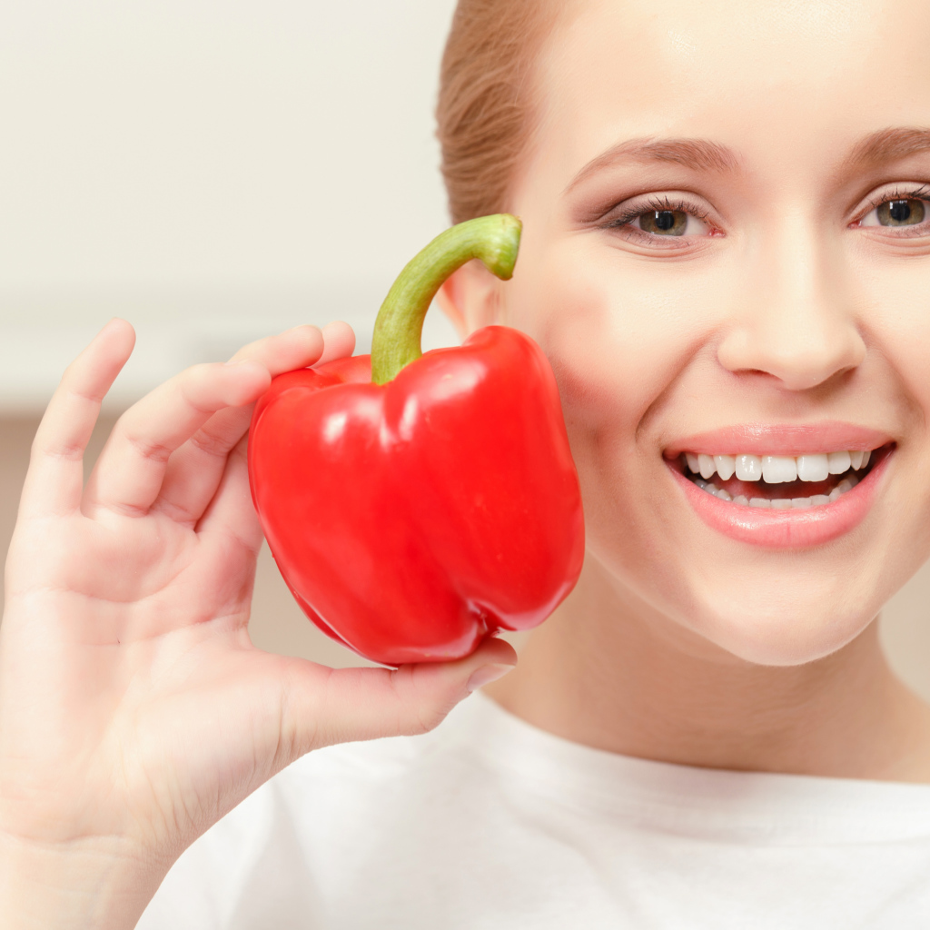Улыбающаяся девушка с красным сладким перцем в руке
