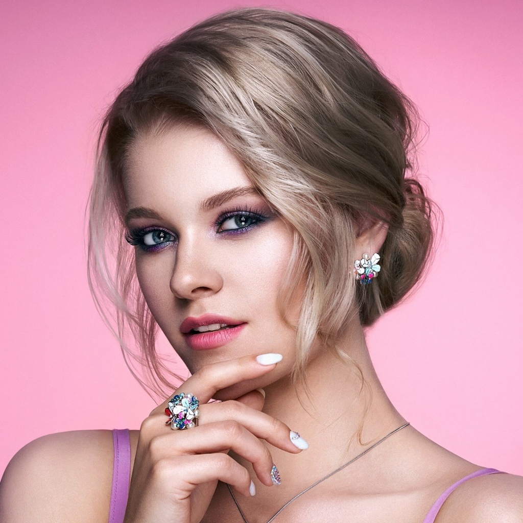 Стильная блондинка с прической на розовом фоне