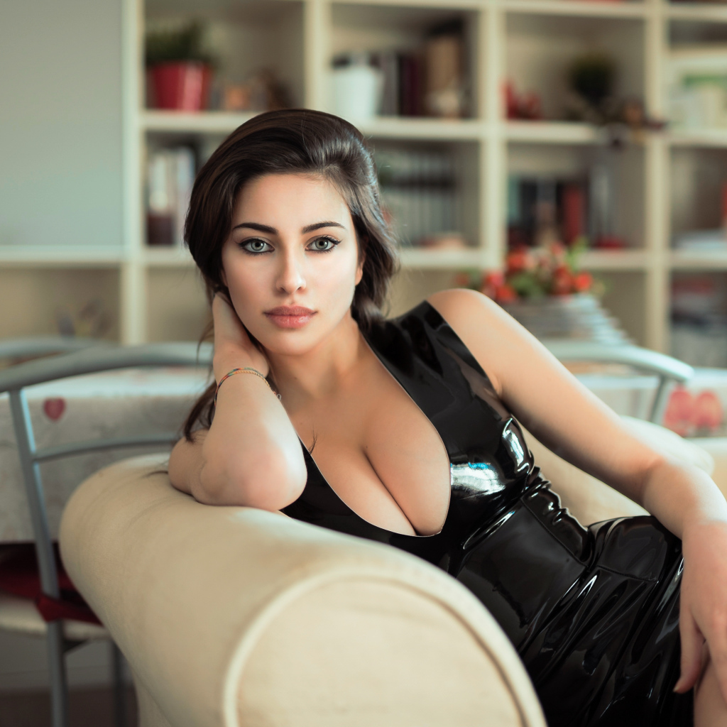 Стильная модная девушка в черном платье на диване