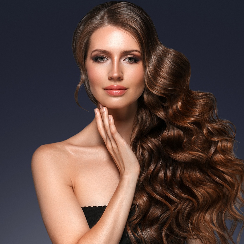 Стильная девушка с красивыми длинными волосами на сером фоне