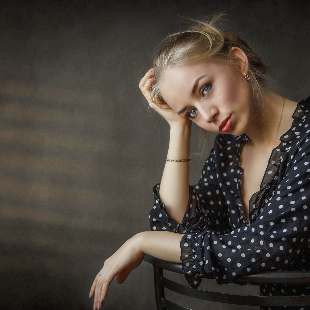 Нежная девушка блондинка сидит на стуле