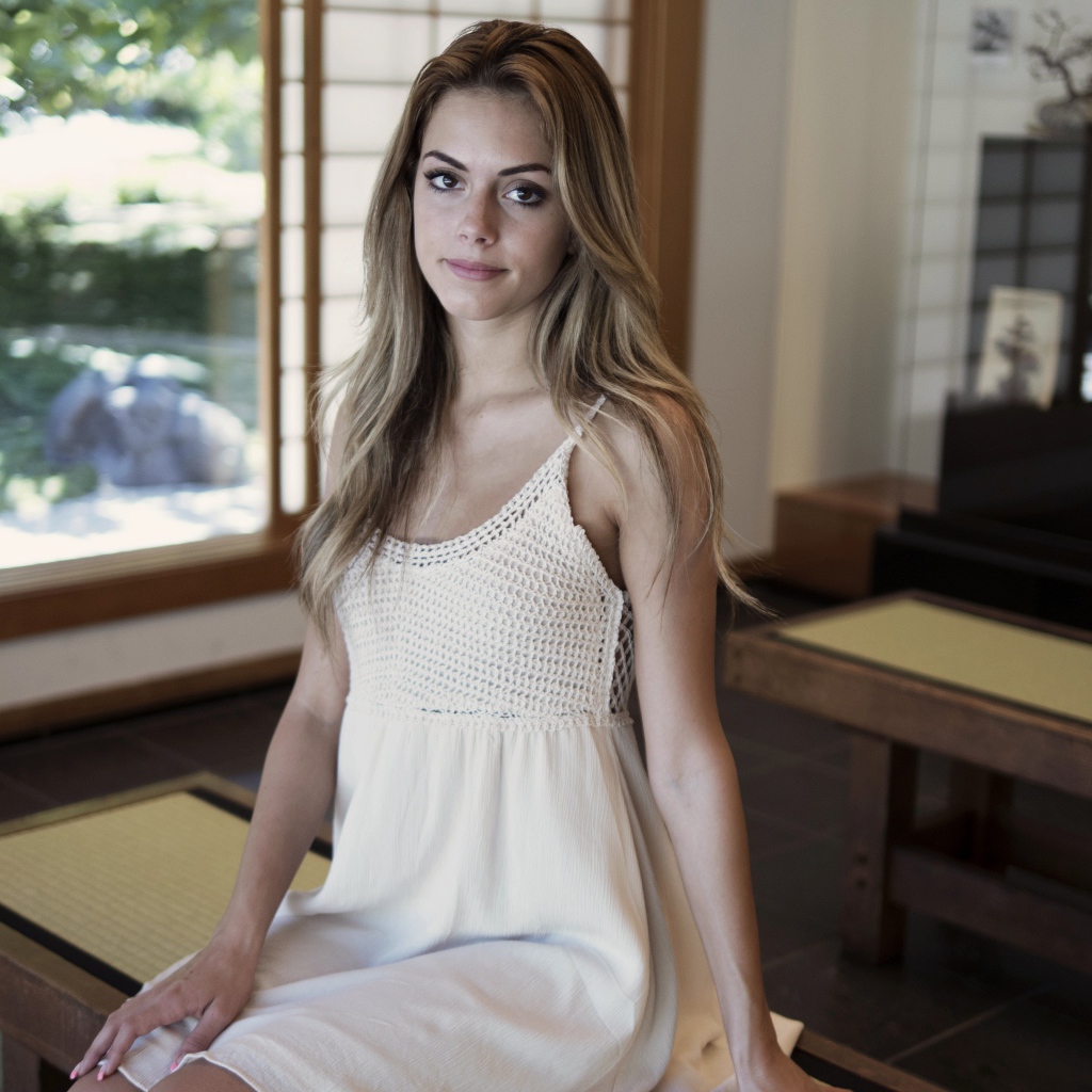 Девушка в белом сарафане сидит на лавке 