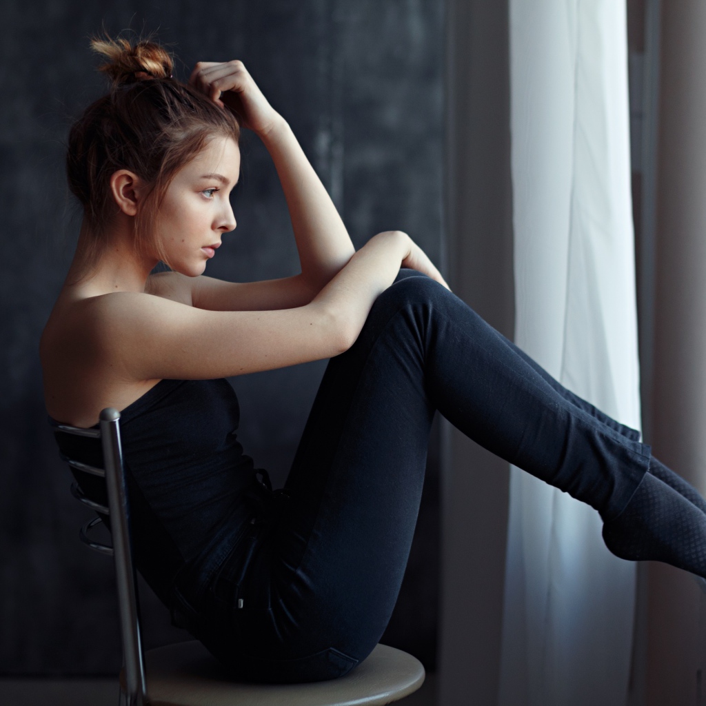 Девушка в черном наряде сидит на стуле