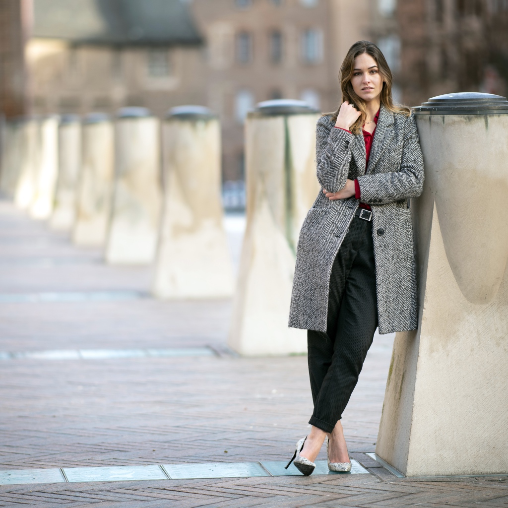 Девушка стоит в сером пальто 