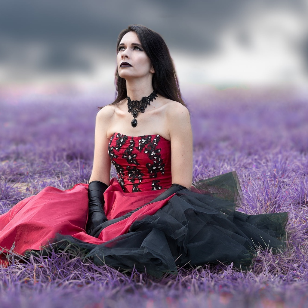 Девушка с макияжем в красивом платье сидит на траве