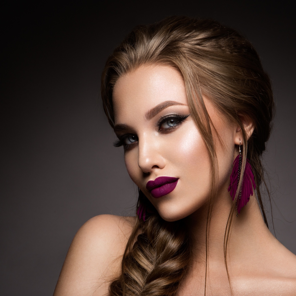 Девушка с ярким макияжем и косой на сером фоне