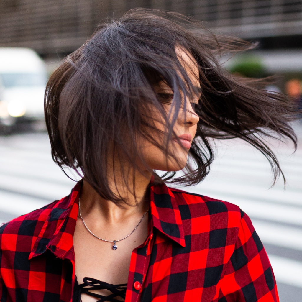 Ветер развивает волосы красивой шатенки в клетчатой рубашке